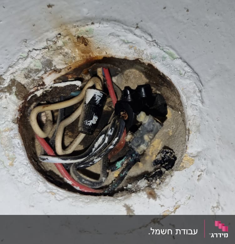 חוטי חשמל חשופים בקיר עם מחברים שחורים